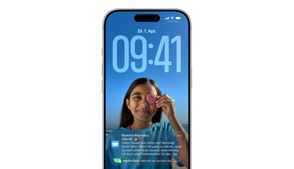 Ein iPhone Sperrbildschirm mit Foto, Ziffern für die Zeitanzeige in Liquid Glass, zwei Mitteilungen erscheinen am unteren Displayrand
