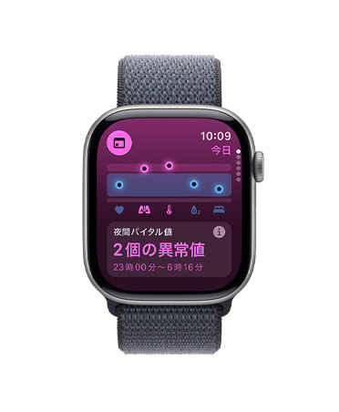 スペースグレイアルミニウムケースのApple Watch Series 11。バイタルアプリに、健康状態を表すグラフ、体に取り込まれた酸素のレベル、夜間バイタル値の異常値を示す通知が表示されている。右側の外観にはDigital Crownがあり、ダークグレイのスポーツループバンドが取りつけられている