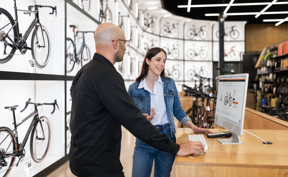 Julien Sicuro, gerente da loja, ajuda uma cliente a escolher uma bicicleta usando a tela Retina brilhante do iMac