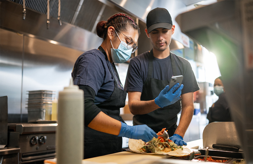 Uma funcionária aprende a enrolar um burrito “à moda Sisig”.