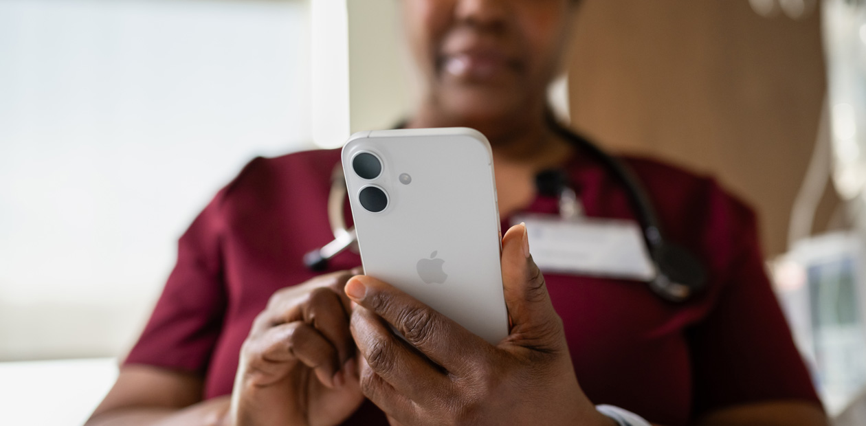 En kvinnelig sykepleier i rød uniform ser på en iPhone.