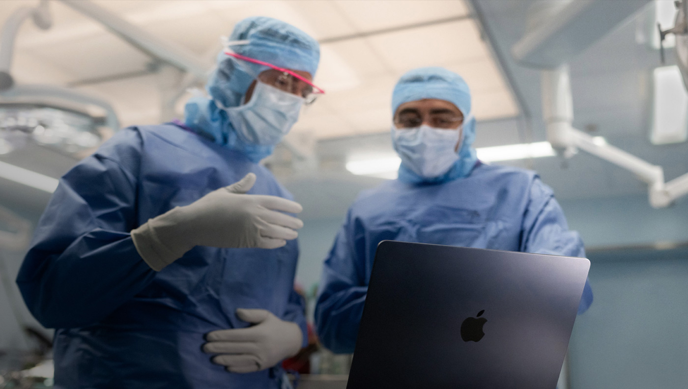 Deux chirurgiens en discussion devant un écran de MacBook Pro au bloc opératoire.