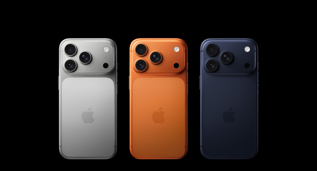 Tre iPhone 17 Pro mostrati da dietro, nei colori argento, arancione cosmico e blu profondo, ciascuno con sistema di fotocamere Pro Fusion nell’angolo in alto a sinistra, tre obiettivi, microfono, flash e logo Apple al centro