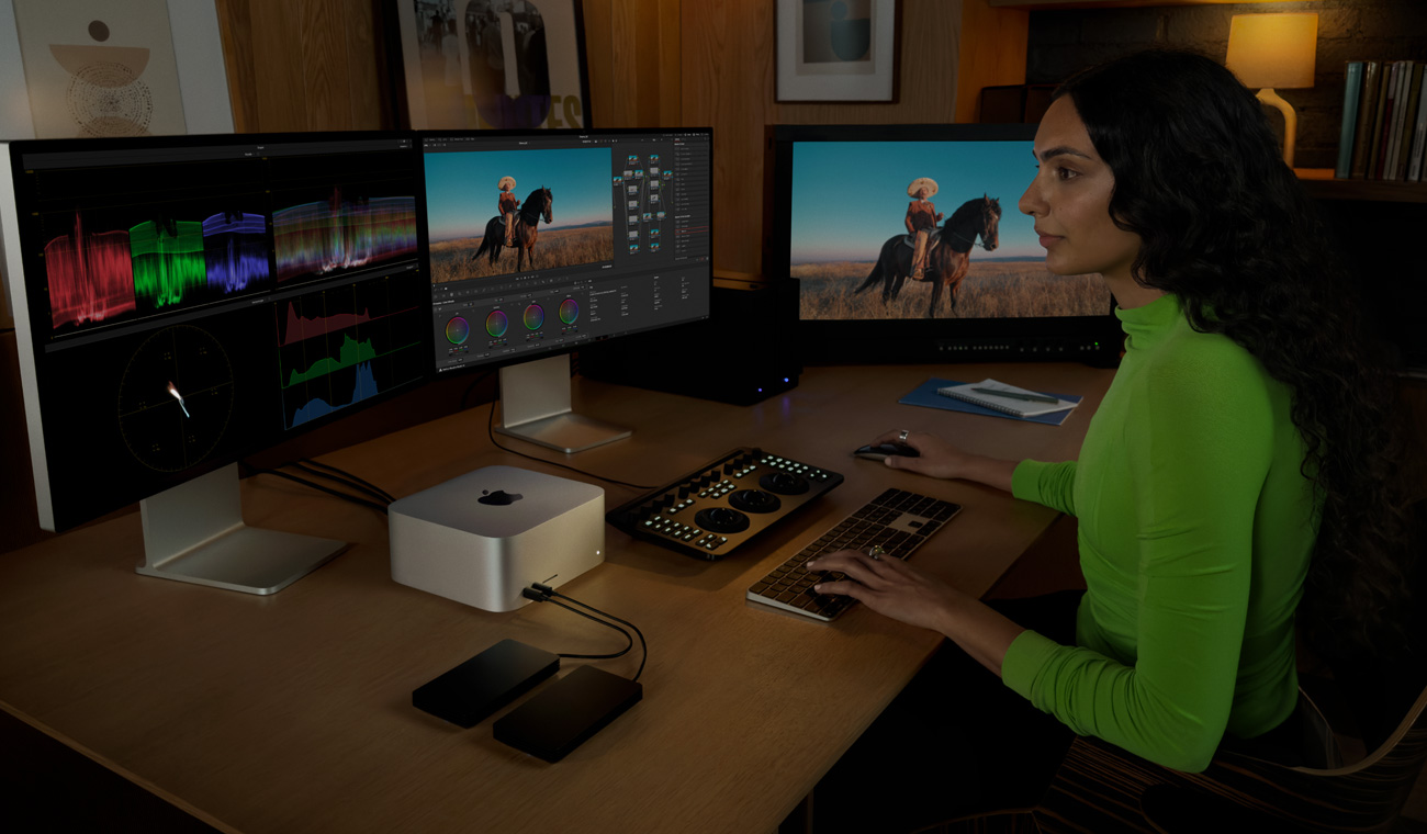 En professionel bruger redigerer indhold på tre skærme, der er forbundet til Mac Studio
